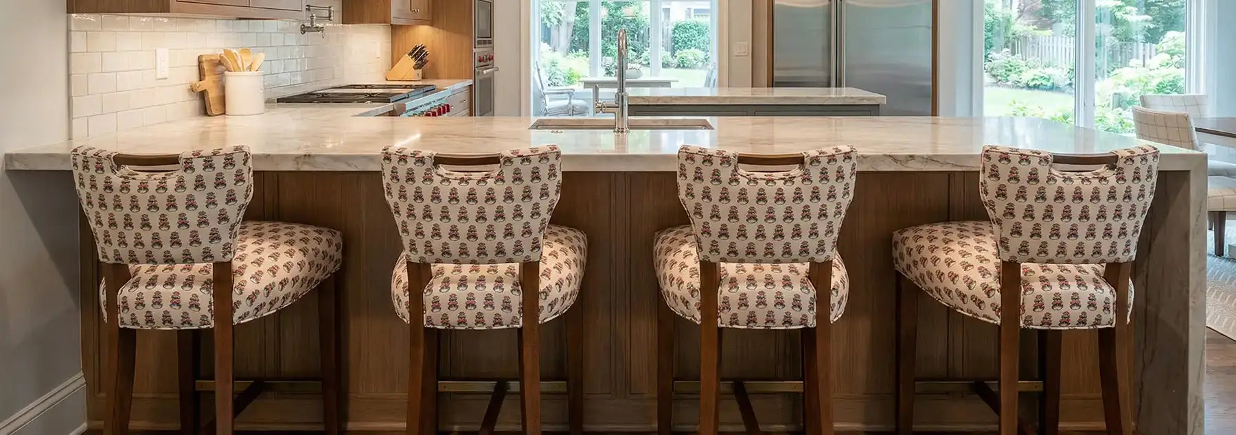 Four patterned bar stools in front of a kitchen counter with a modern kitchen in the background.