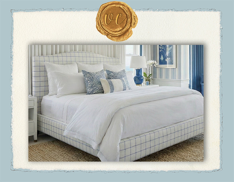 Bedroom with a bed featuring white bedding and decorative pillows, with a decorative headboard and lamp in the background.