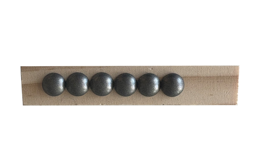 Row of six metallic nailheads on a wooden strip with a white background