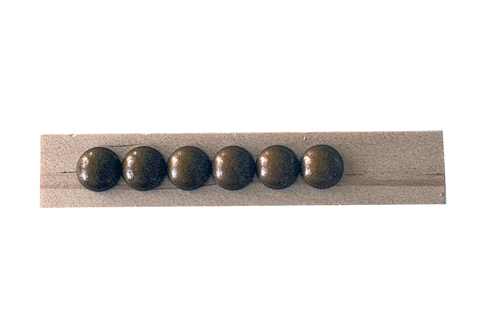 Row of six metallic nailheads on a wooden stick against a white background