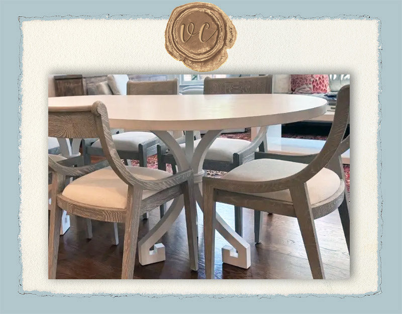 Dining table with chairs in a room setting, featuring a brand logo at the top.